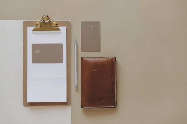 Flat lay of a minimalist office desk with clipboard, credit cards, pen, and leather wallet. Payment reconciliation